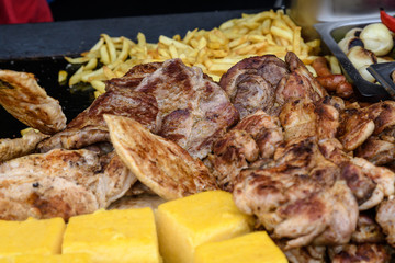 Bunch with different kinds of grill steaks with blurred polenta in the foreground and  blurred fries in the background