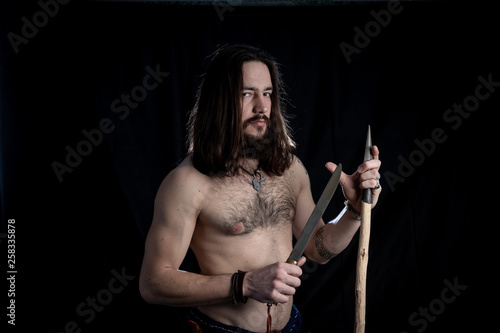 A Strong Bearded Long Haired Man With A Tattoo On His Shoulder