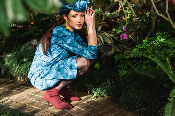 Sad pensive woman in blue dress and turban sitting in botanical garden