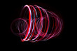 Light painting of red and continuous white spirals forming a 3D shape. Dynamic time trajectory of two lights simultaneously.