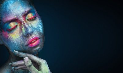 Beauty portrait of young woman with blue artistic makeup