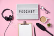 Music or podcast background with headphones, microphone, coffee and blank on pink table, flat lay. Top view, flat lay