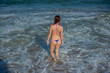 © Михаил Решетников - Beautiful young woman in a seductive bikini walks into the sea with high waves. Big waves in the ocean