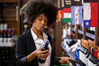 © paulovilela - African business Woman holding bottles of wine in supermarket