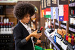 © paulovilela - African business Woman holding bottles of wine in supermarket