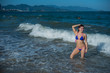 © Михаил Решетников - beautiful young woman in a seductive bikini comes out of the sea with high waves. Big waves in the ocean