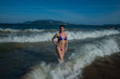 © Михаил Решетников - beautiful young woman in a seductive bikini comes out of the sea with high waves. Big waves in the ocean