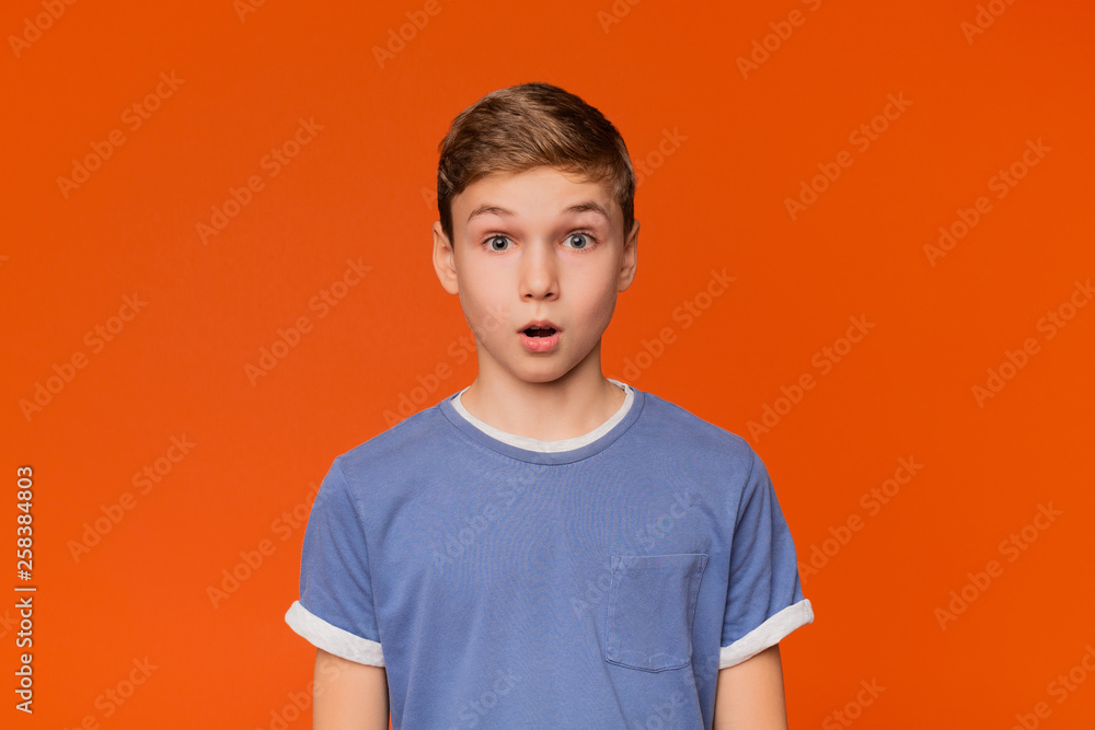 Portrait of stunned boy on orange studio background - obrazy, fototapety, plakaty 