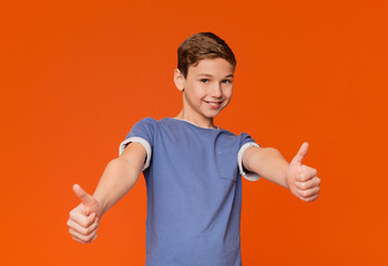 Cool boy doing thumbs up gesture on orange