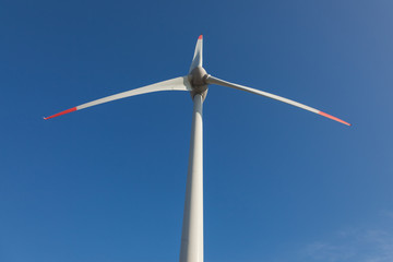 wind turbine with sun flare blue sky background view from below