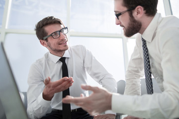 employees discuss something sitting in front of an open laptop.