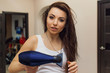© Катя Датунова - young woman in a white T-shirt dries her hair with a hair dryer, shows emotions, is going to go out in people, close-up. beauty concept