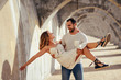 © Westend61 - Spain, Andalusia, Malaga, happy man carrying girlfriend under an archway in the city