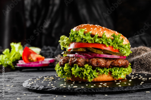 wolowina-hamburger-z-pomidorami-czerwonymi-cebulami-ogorkiem-i-salata-na-czern-lupku-nad-ciemnym-tlem-niezdrowe-jedzenie
