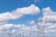 Large high tension power lines with cables and structures showing on a parlty cloudy and sunny day with blue skies
