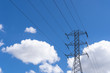 Large high tension power lines with cables and structures showing on a parlty cloudy and sunny day with blue skies