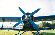 Small Plane With Propeller On A Background Of Green Grass And Clear Sky.