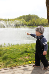 Pointing with a finger by a boy. A small child with his finger up. The concept of pointing something, paying attention to something.boy shows in the direction of the fountain and the lake