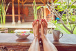 © astrosystem - Woman's feet on a desk in a tropical backyard.