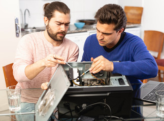 Two men repairing a desktop computer