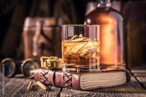Fotografía Closeup of whisky with ice on old journal