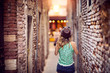 Girl with a hat walking and discovering places in narrow street.