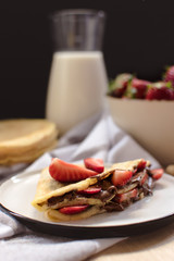 Wall Mural - crepes with strawberries and chocolate cream, black background