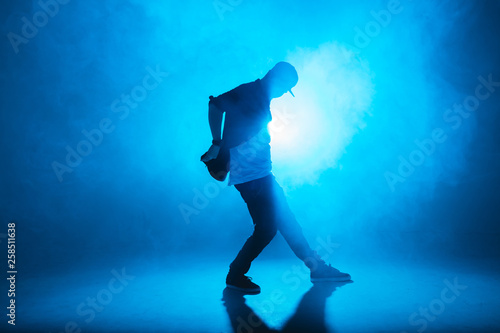 Fototapety Rap  ciemna-sylwetka-piosenkarza-na-scenie-tanczacego-samotnie-podczas-wystepu-na-ciemnoniebieskim-neonu