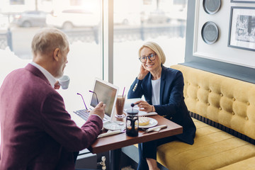 old elegant man and woman enjoying business meeting indoors, hobby, pleasant time with partners. happiness