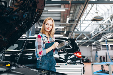 Wall Mural - good looking woman in uniform writing something on a computer, new device for testing a vehicle, close up photo