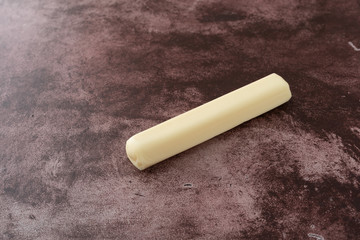 Mozzarella snack string cheese stick on a red background side view