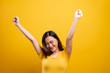 Happy woman make winning gesture isolated over yellow background