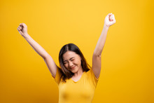 Happy Woman Make Winning Gesture Isolated Over Yellow Background