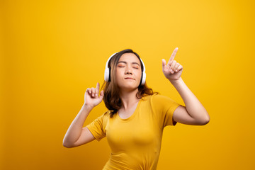 Woman with headphones listening music on isolated yellow background