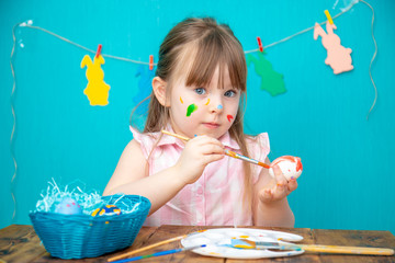 Happy little girl painting easter egg