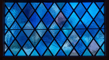 Detail Of Blue Diamond Shaped Panes In Colored Light From Stained Glass Window In Catholic Church