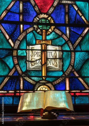 Fotografía Colored light from stained glass window in methodist church falls across open bi