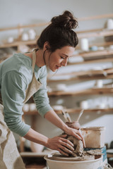 Wall Mural - Beautiful young woman in apron working in pottery workshop