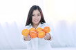 © kaew6566 - Lifestyle and healthy food concept. Focus hands of smile young woman holding fresh oranges fruit in her hand on white bed at home with copy space. Focus oranges fruit.
