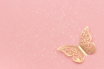 Sparkles glitter and gold tracery butterfly on pink pastel trendy background. Festive background, template
