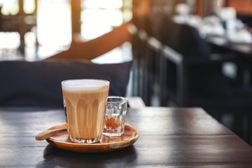 Closeup image of a glass of hot coffee on wooden table in cafe