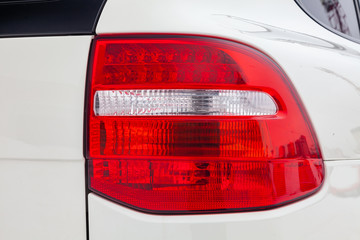 Wall Mural - Rear tail lamp view of car in white color after cleaning before sale in a winter day and snow parking background