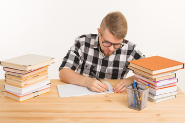 People and education concept - the guy sits at the table and makes notes in a notebook