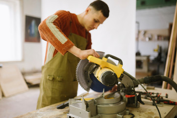 Master works as a circular saw in the carpentry workshop