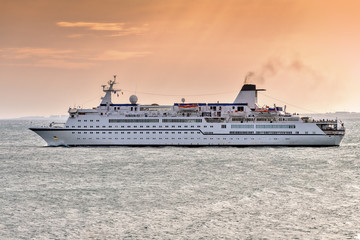 Canvas Print - Cruise ship sailing off the coast during sunset.