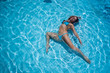 © Михаил Решетников - Over head rear view of an attractive young woman swimming under water and wearing in bikini