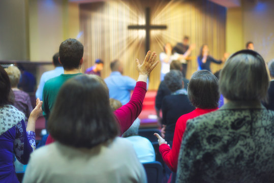 Christian congregation worship God together, with cross with light rays in background