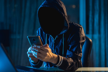anonymous hacker programmer uses a laptop to hack the system in the dark. concept of cybercrime and 