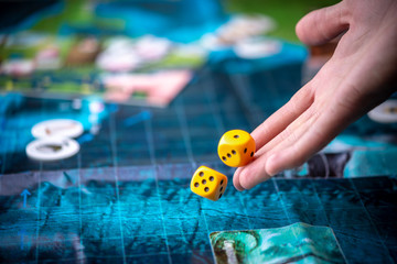 Hand throws two yellow dice on the blue field of the fantasy game. Gaming moments in dynamics. Board games strategy