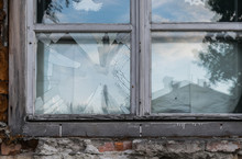 Broken Glass Windows In An Old House. Reflection Of The Sky And Houses In Shattered Glass.